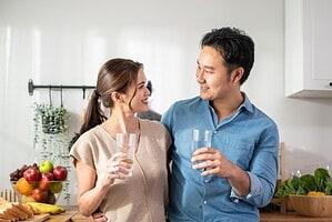 ผู้หญิงและผู้ชายดื่มน้ำสะอาดที่ได้จากเครื่องกรองน้ำ