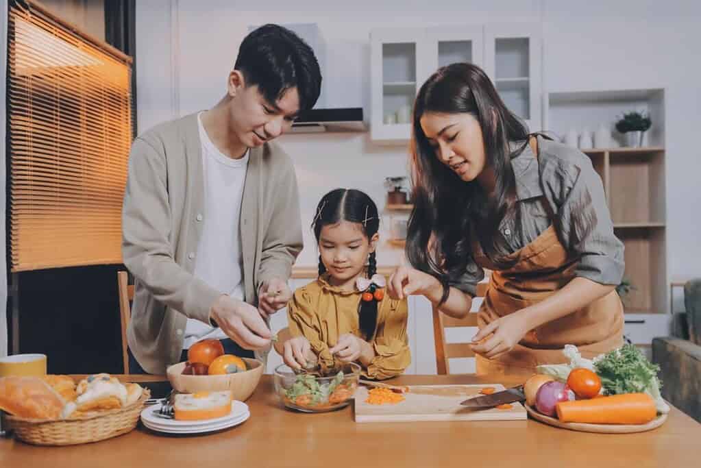A family preparing dinner in their small condo kitchen, which also has a slim, space-saving water dispenser.