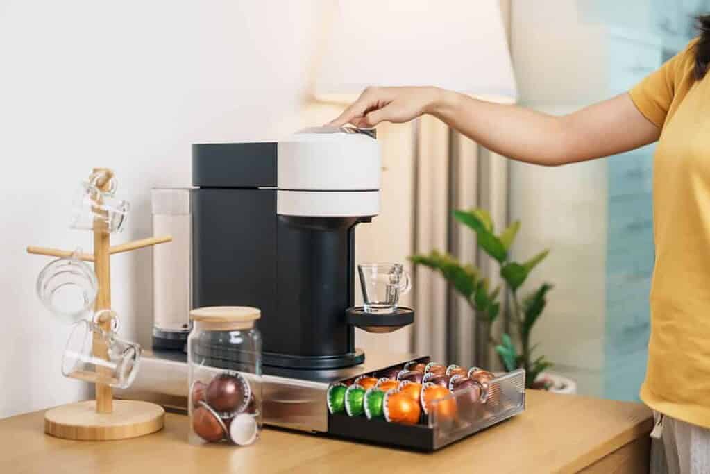 A woman enjoying her home cafe corner ideas by using a capsule coffee machine.