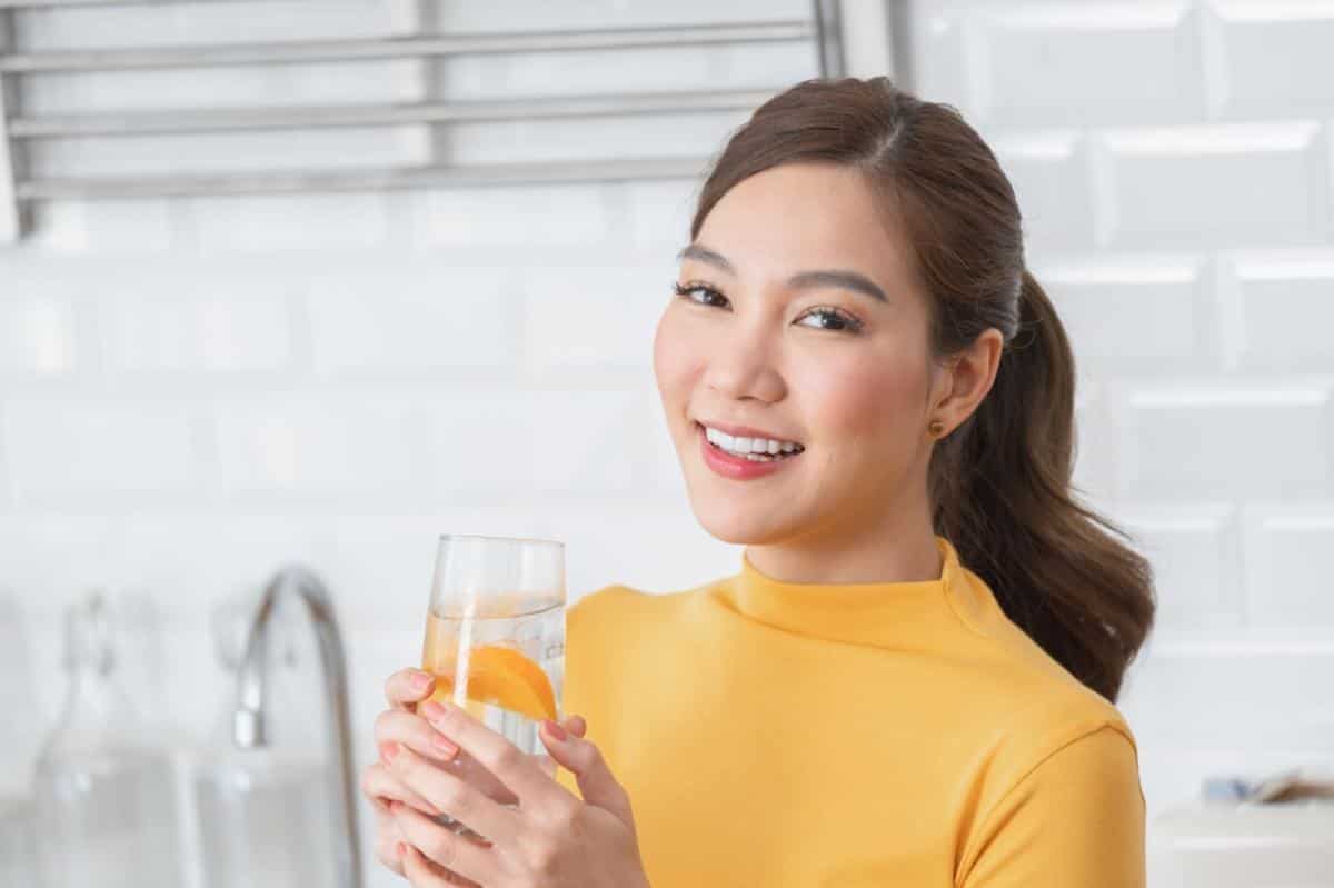 A woman drinking infused water to stay refreshed during the day.